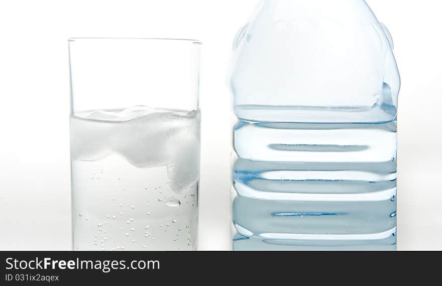 A bottle of fresh mineral water and a glass which is poured the same water on a white background