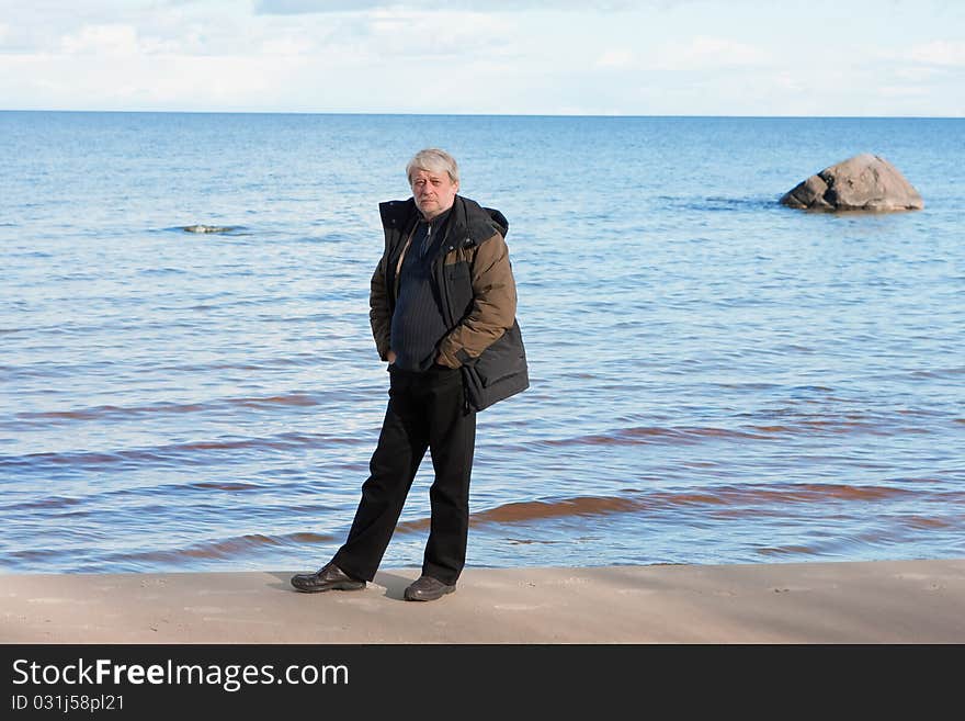 Mature man with grey hair relaxing at the Baltic sea in autumn day. Mature man with grey hair relaxing at the Baltic sea in autumn day.