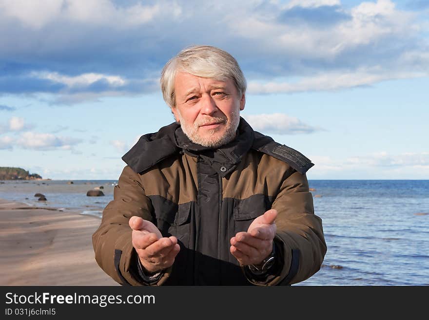 Mature poor man with grey hair at the Baltic sea asks for help in autumn day. Mature poor man with grey hair at the Baltic sea asks for help in autumn day.