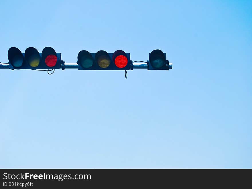 Red color on the traffic light on the blue sky background