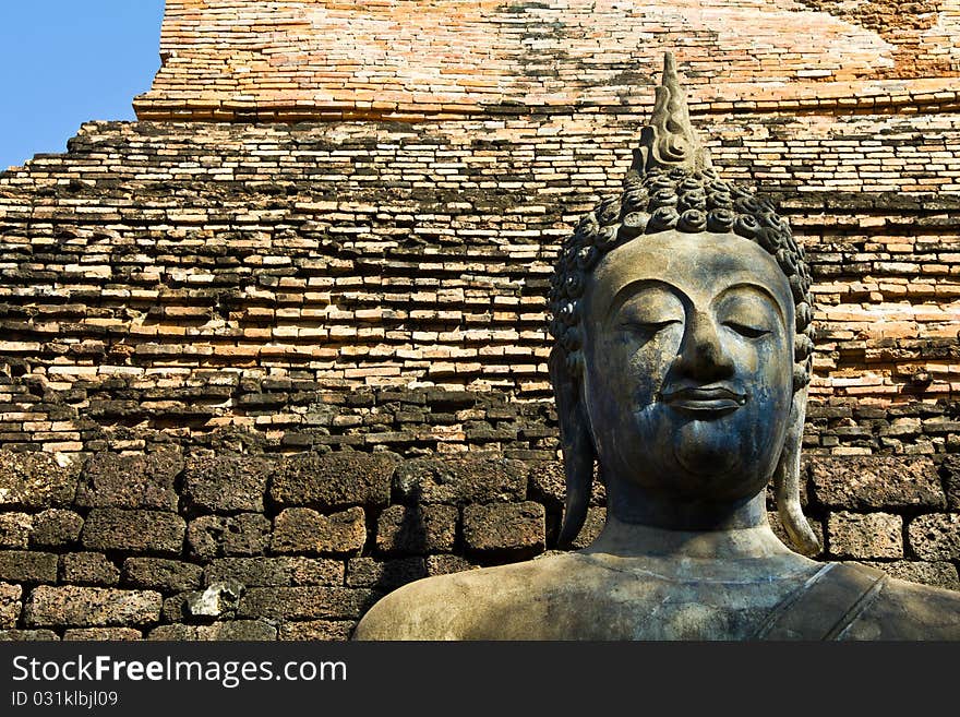 Ancient Buddha statue with brick wall