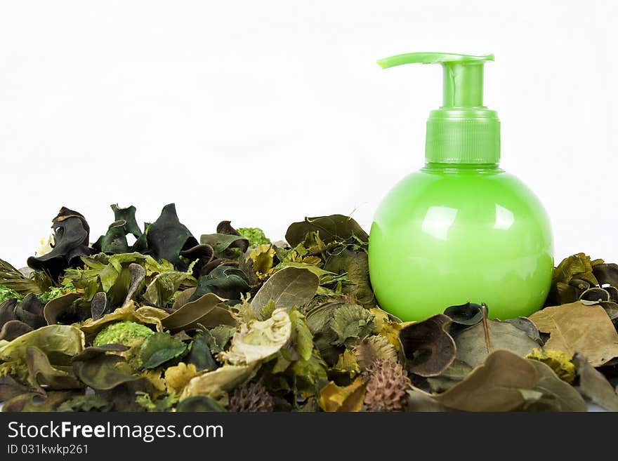 Green cream bottle with some dry leaves isolated on white background