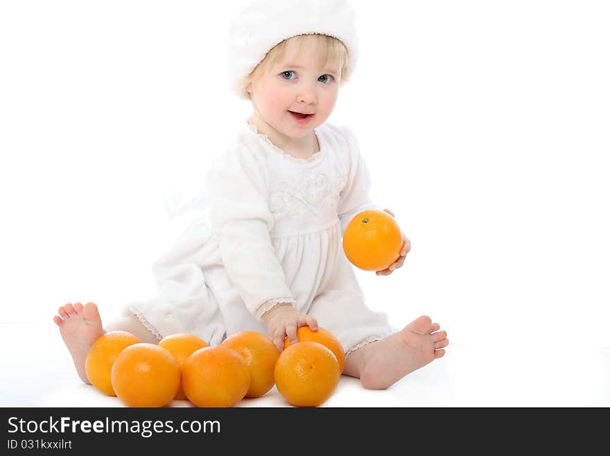 Smiling barefooted baby with oranges