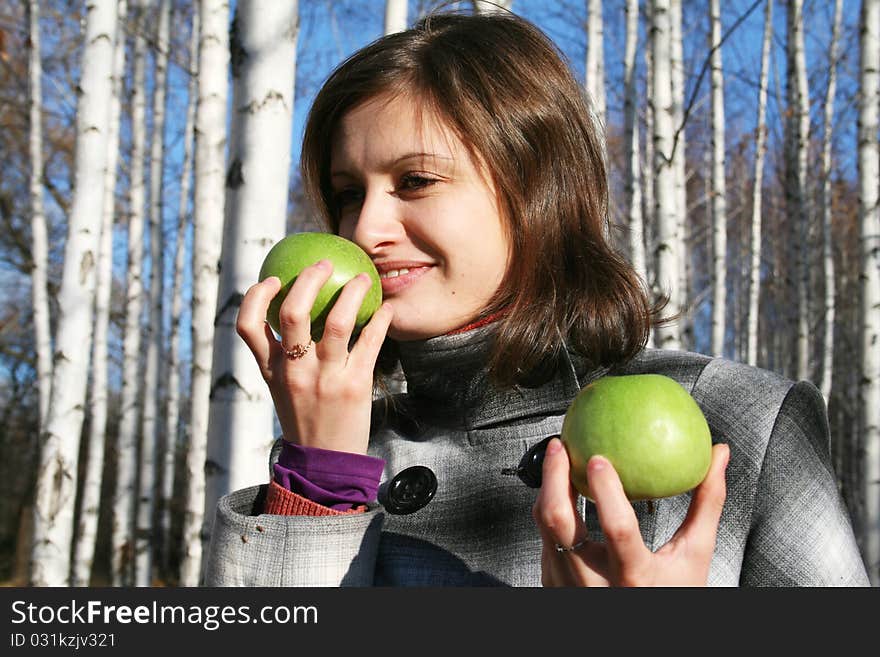 The young girl in a checkered coat with two green apples. The young girl in a checkered coat with two green apples