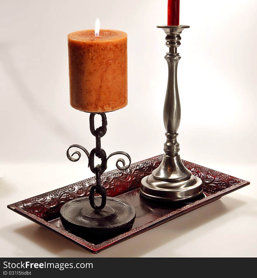 Two candles in their candle holders sitting in a bronze platter. Two candles in their candle holders sitting in a bronze platter.