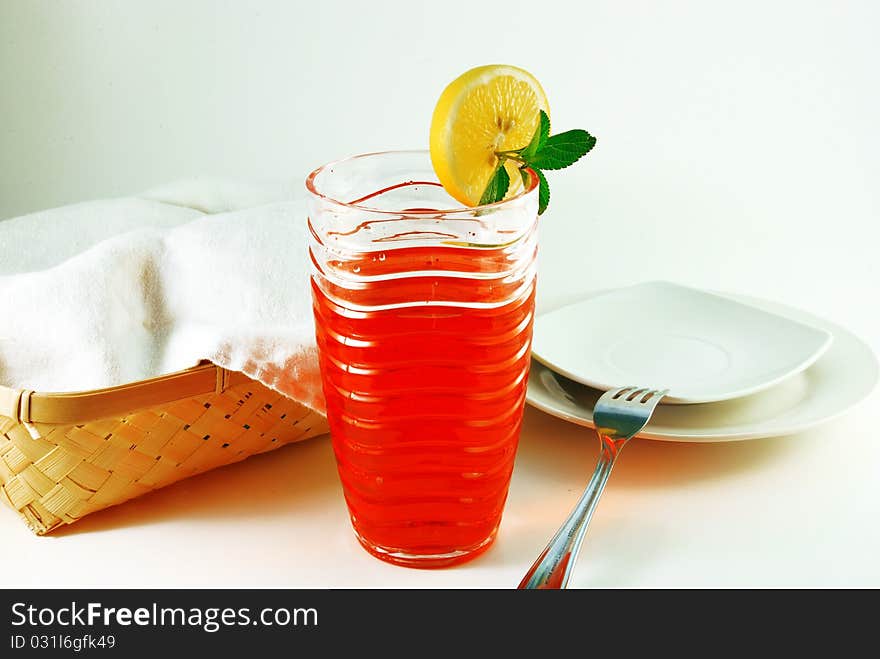 Cherry juice in a glass with a lemon on a white background. Cherry juice in a glass with a lemon on a white background