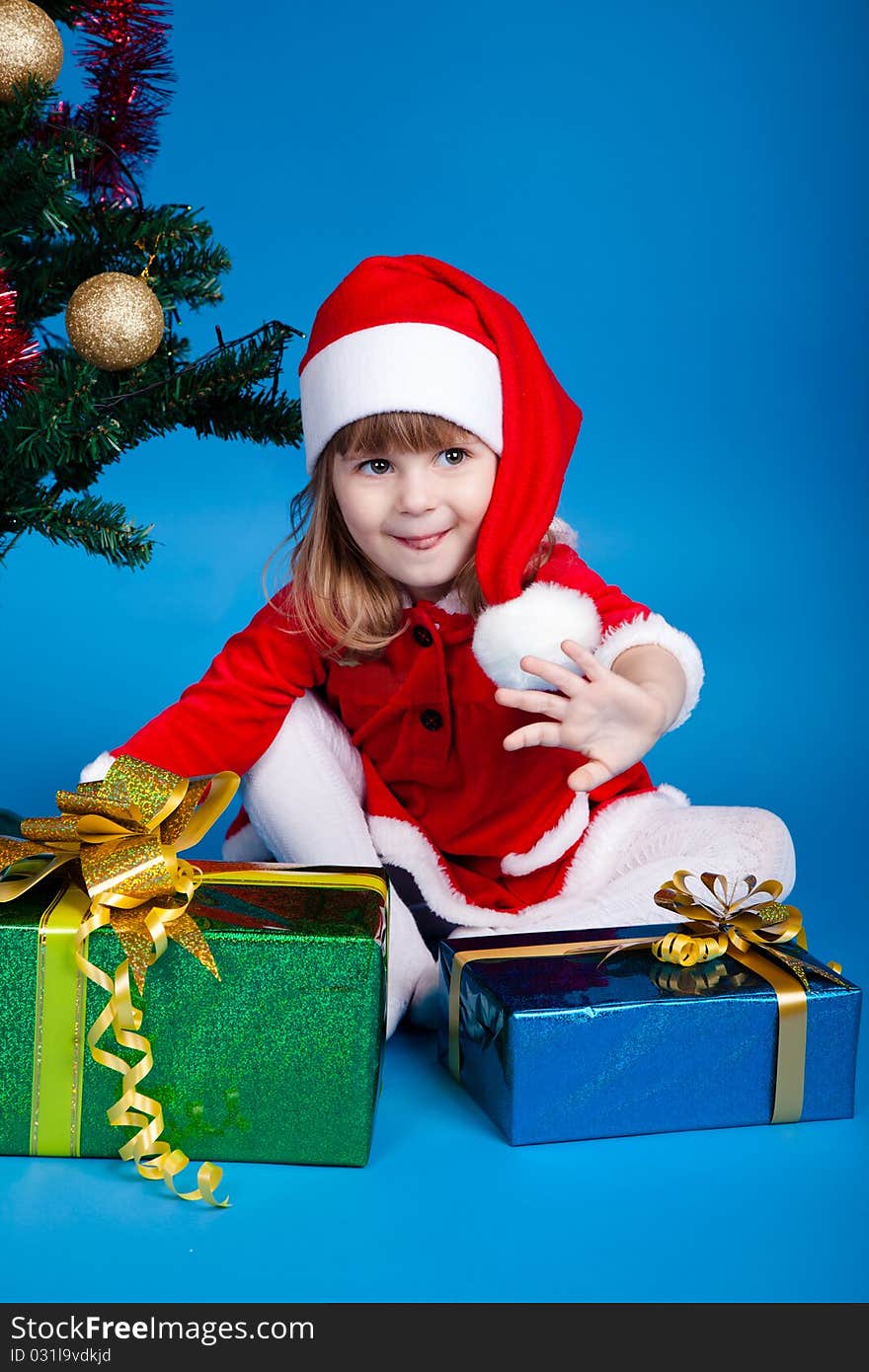 Girl in Santa costume playing with gifts