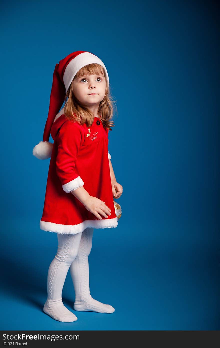 Sweet little girl dressed in santa costume on dark blue background