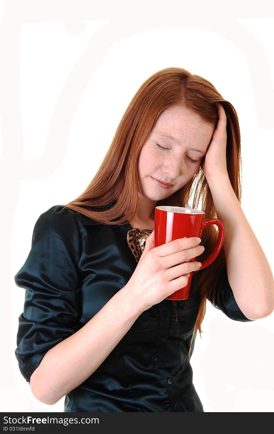 A young woman with long red hair with a headache holding her head
and a mug of coffee, in a green blouse for white background. A young woman with long red hair with a headache holding her head
and a mug of coffee, in a green blouse for white background.