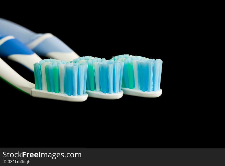 Three toothbrushes isolated on a black background.