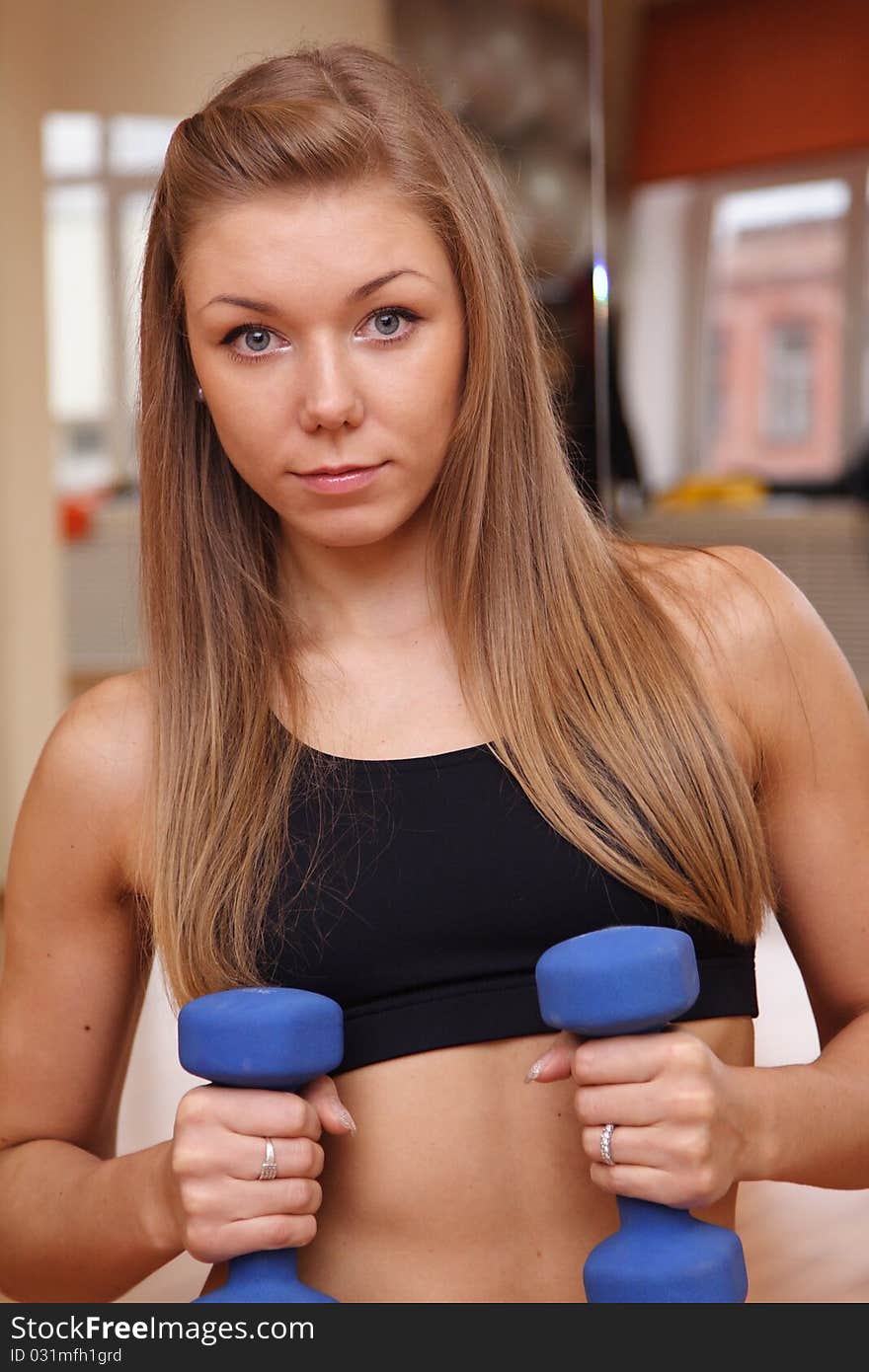 Girl hold dumbbells in hand with strong abdomen