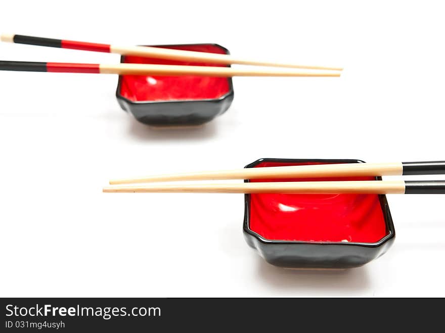 Black and red chopsticks and plates isolated on white background