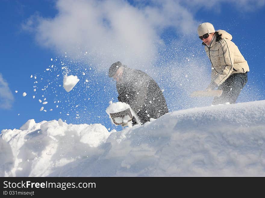 A man and young woman removing snow from a roof. A man and young woman removing snow from a roof