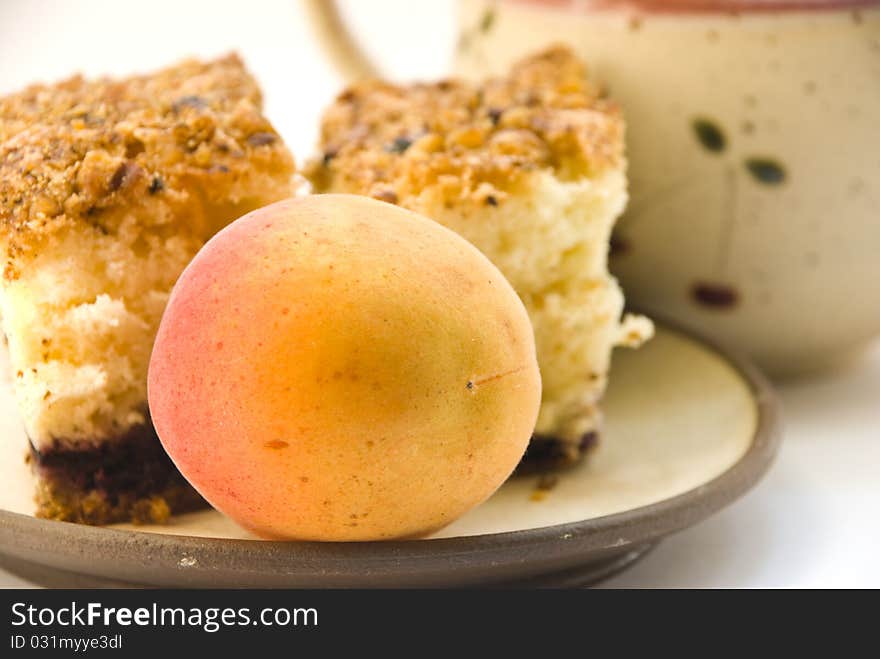 Apricot on a plate next to the cake, close-up. on a white background. Apricot on a plate next to the cake, close-up. on a white background