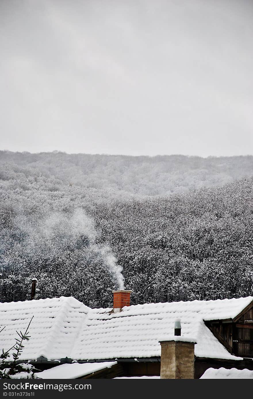 A beautiful snowy landscape whit smoking chimney in Hungary