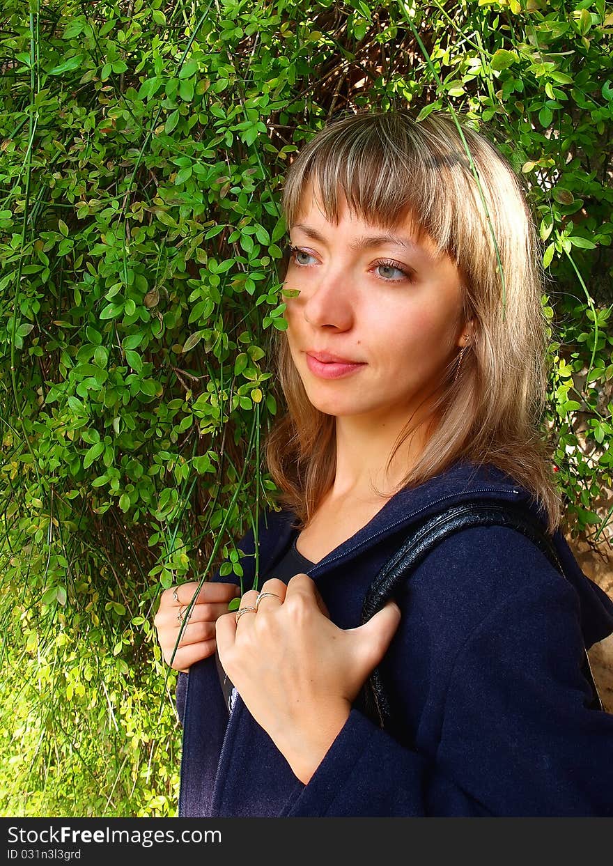 Portrait of a young blonde woman standing in a green fresh bushes. Portrait of a young blonde woman standing in a green fresh bushes