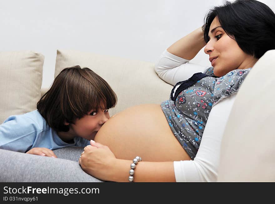 Young boy kissing pregnant belly. Young boy kissing pregnant belly