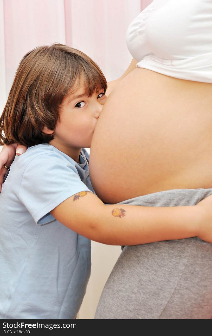 Young boy kissing pregnant belly. Young boy kissing pregnant belly