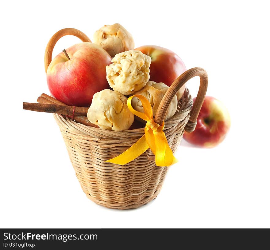 Red apples and cookies and cinnamon in a small basket. On a white background. Red apples and cookies and cinnamon in a small basket. On a white background