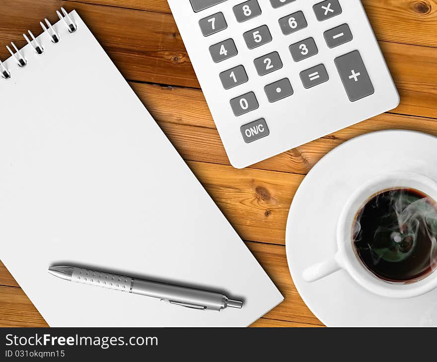 White calculator and white note paper with pen and white cup of hot coffee on wood table