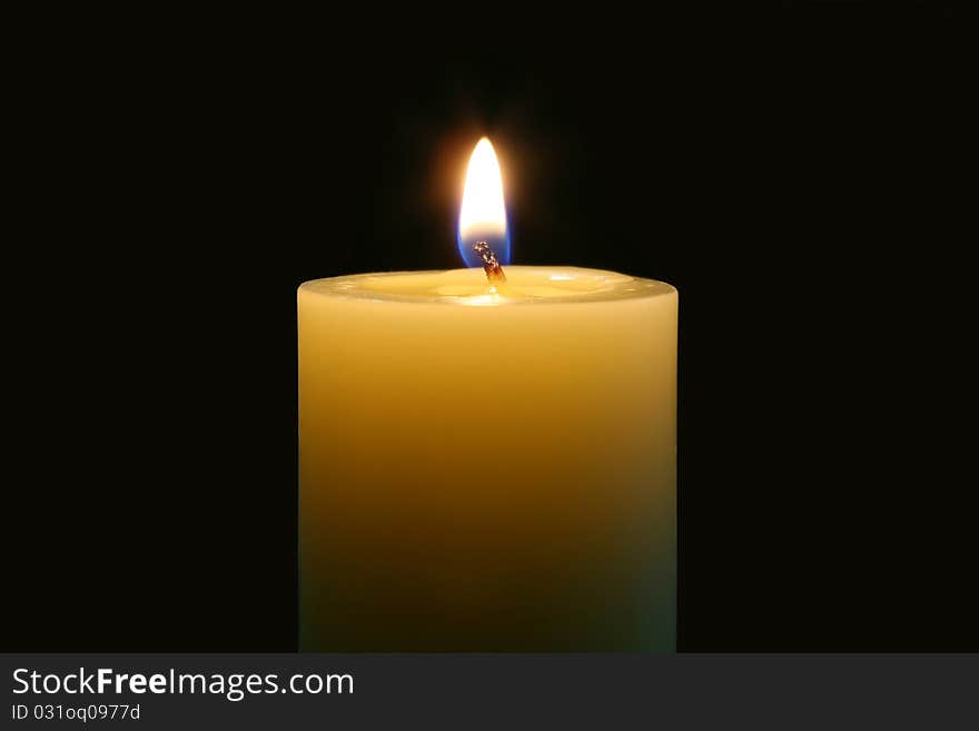 A single burning candle isolated with black background