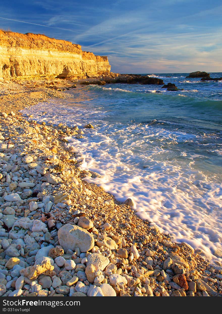 Seashore with round stone and blue wave