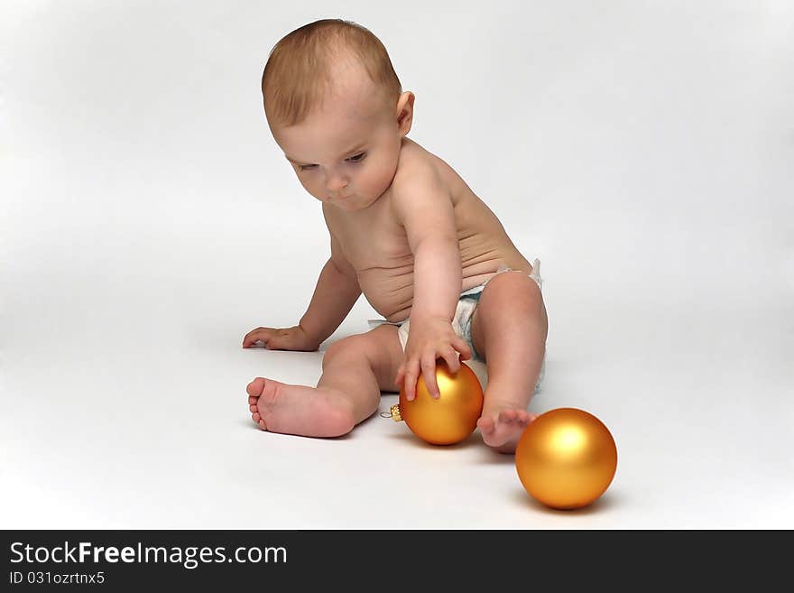 Baby playing with the Christmas glass ball on the white background. Baby playing with the Christmas glass ball on the white background