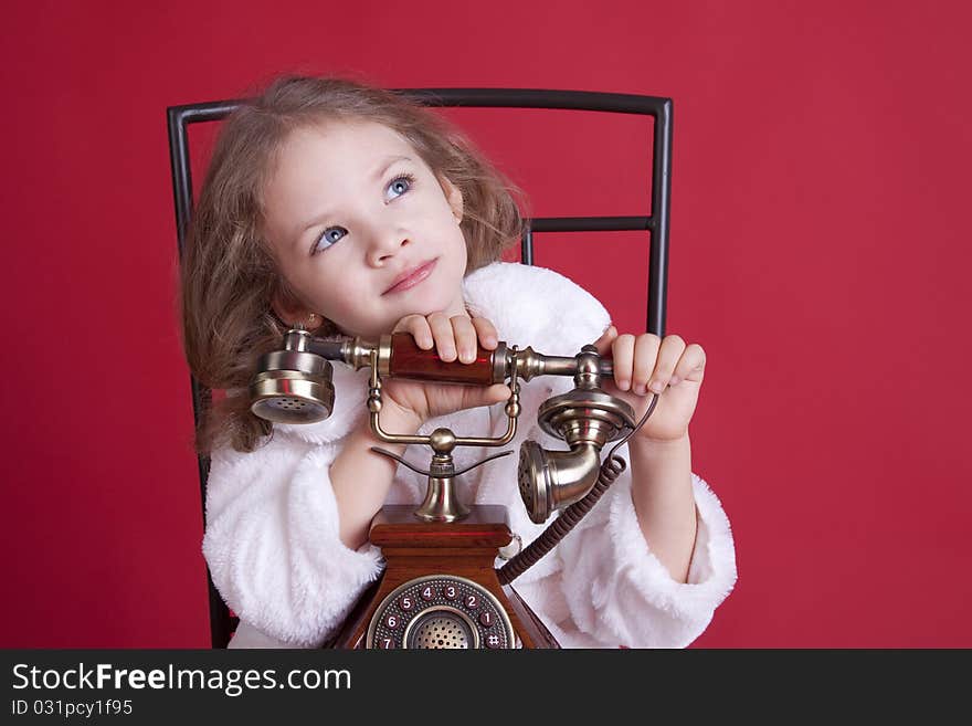 Portrait of a celebatory dressed cute dreamy little girl with an old phone. Portrait of a celebatory dressed cute dreamy little girl with an old phone