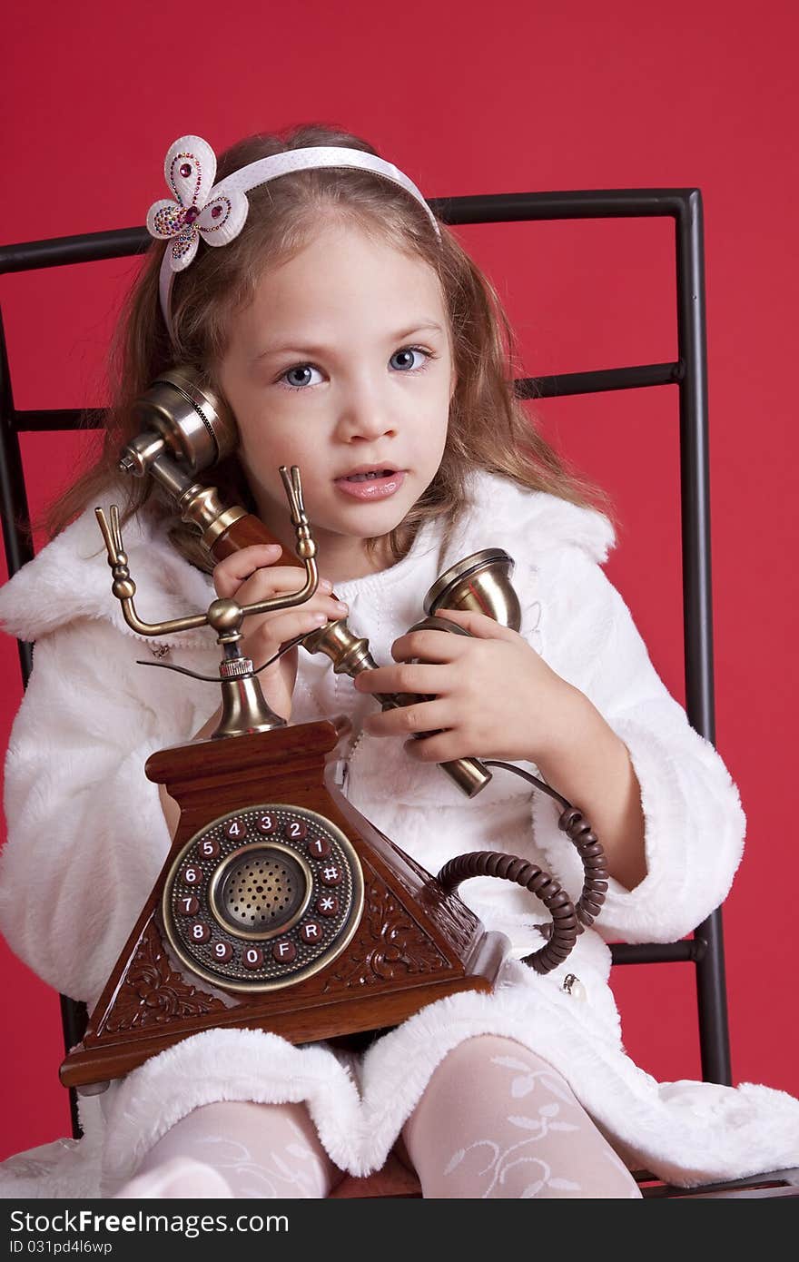 Portrait of a celebatory dressed cute  little girl talking by an old phone. Portrait of a celebatory dressed cute  little girl talking by an old phone