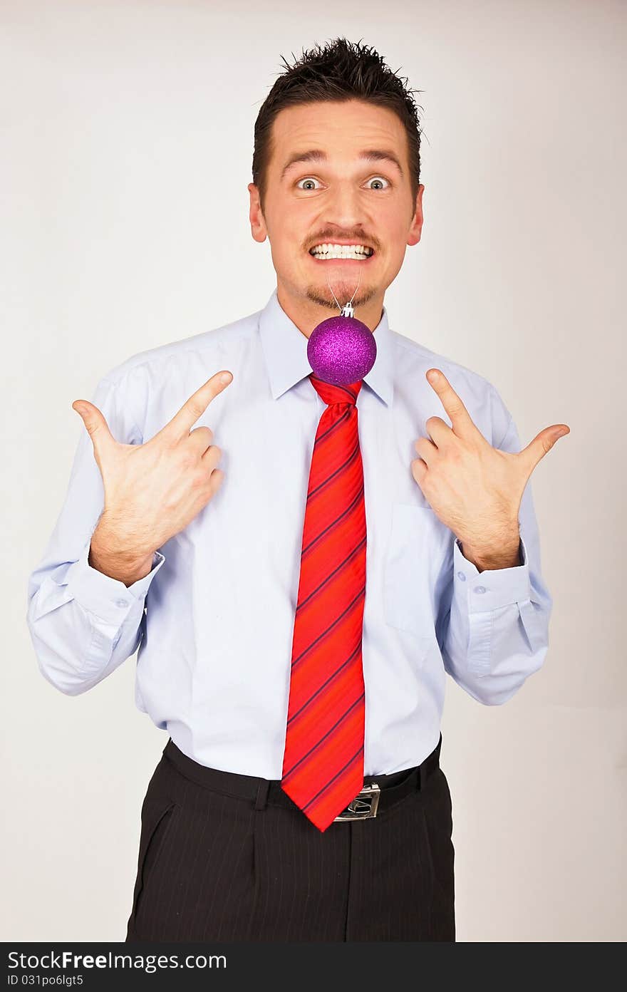 Young man in shirt and red tie has Christmas Ornament between teeth. Young man in shirt and red tie has Christmas Ornament between teeth.