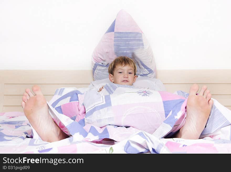 Child and parent's feet looking out from under blanket