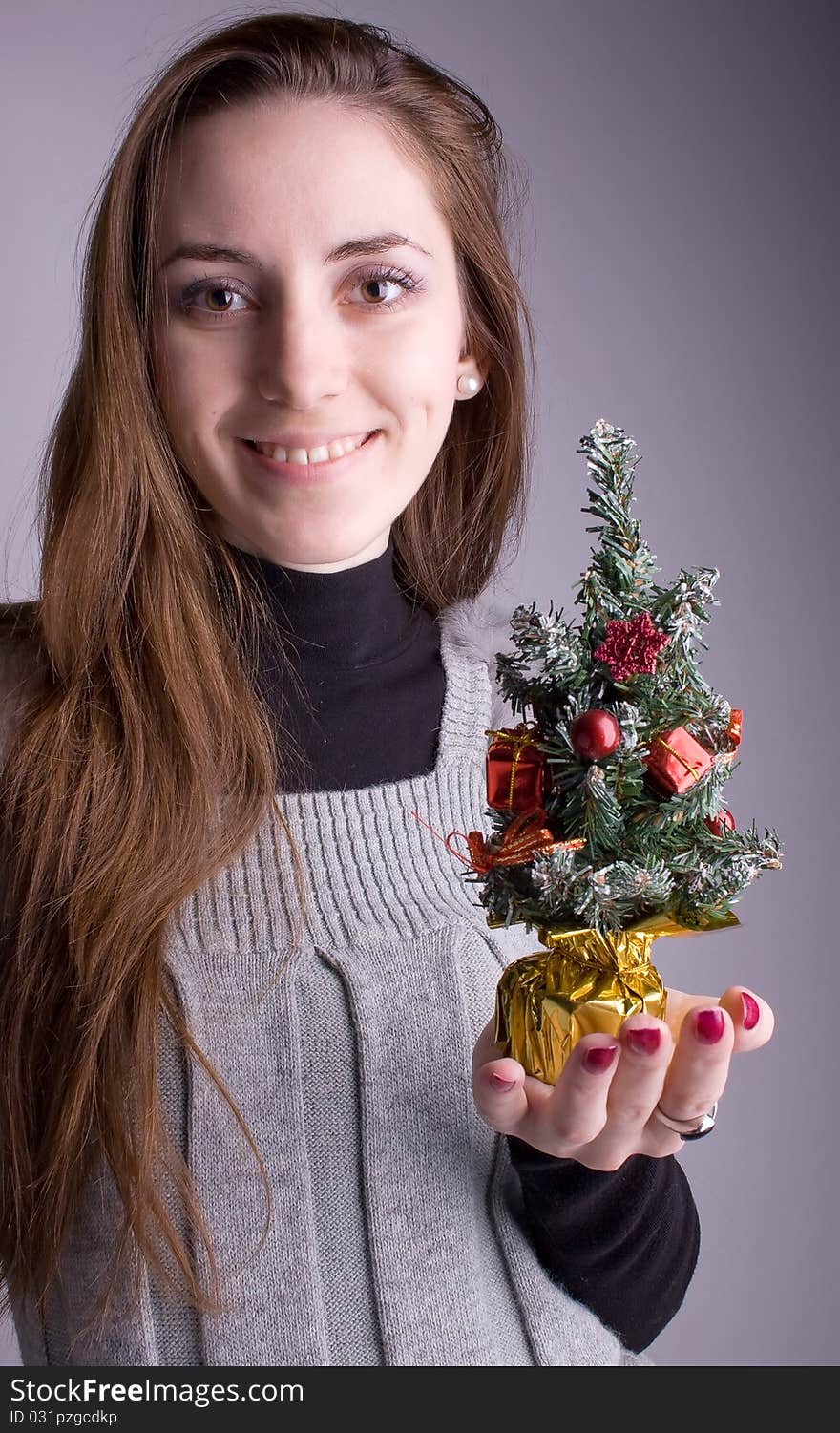 Beautiful girl smiling and holding a Christmas tree in hand