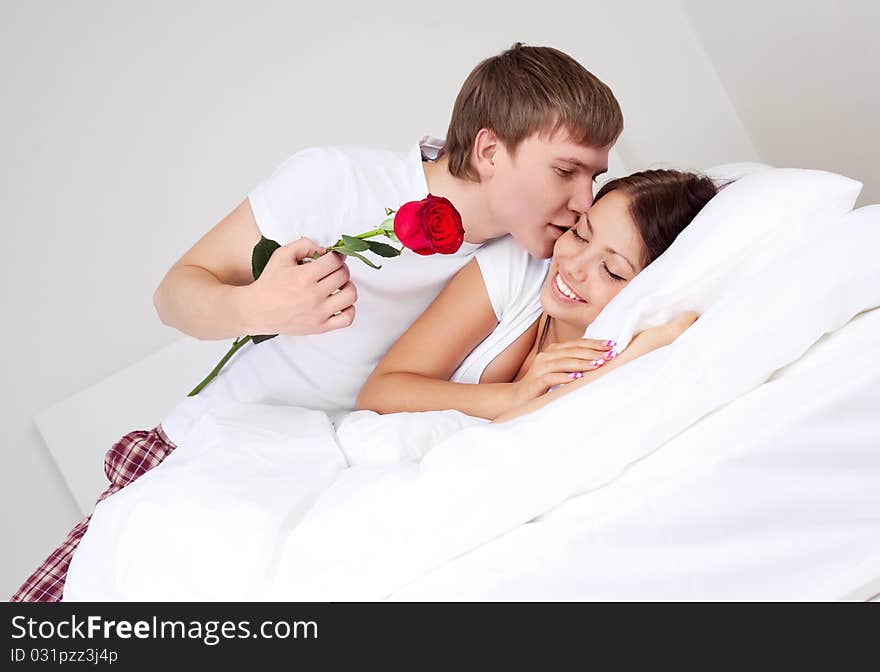 Young man kissing his beautiful girlfriend and giving her a rose (focus on the man). Young man kissing his beautiful girlfriend and giving her a rose (focus on the man)