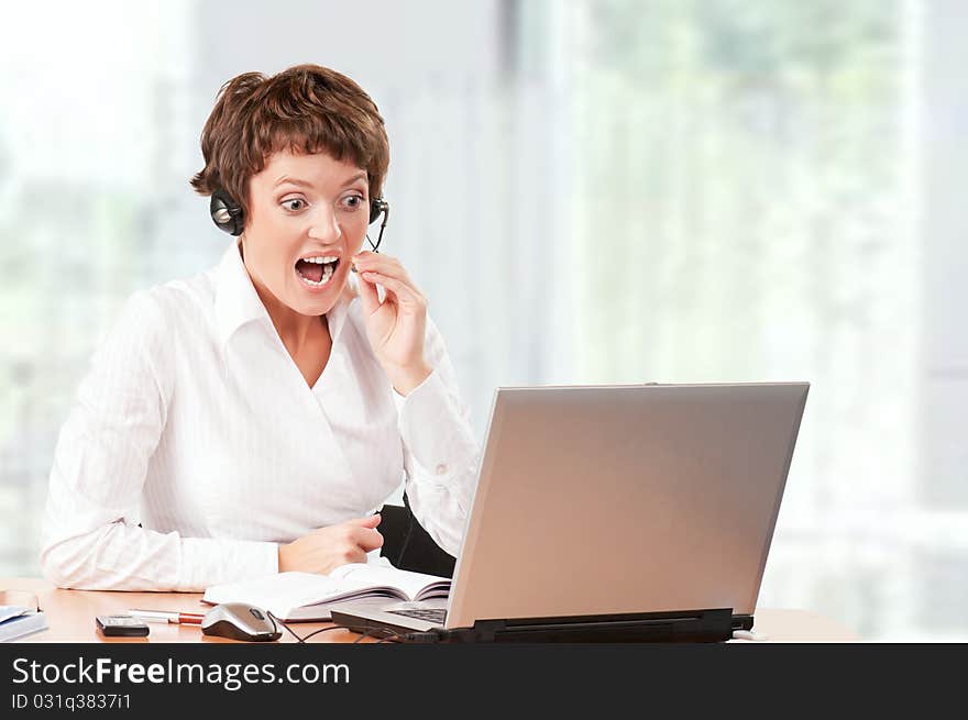 Beautiful businesswoman working with laptop and headset at her office. Beautiful businesswoman working with laptop and headset at her office