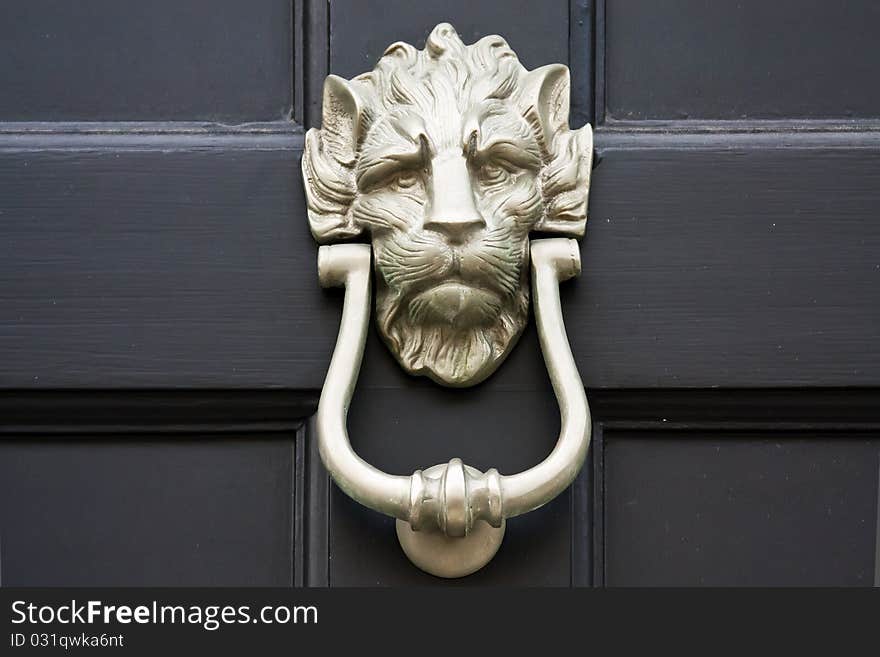 Lion shaped brass door knocker. Close up over black background. Lion shaped brass door knocker. Close up over black background