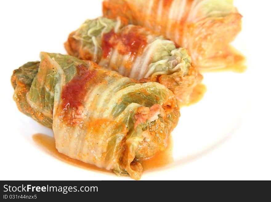 Three stuffed cabbage with tomato sauce on a white