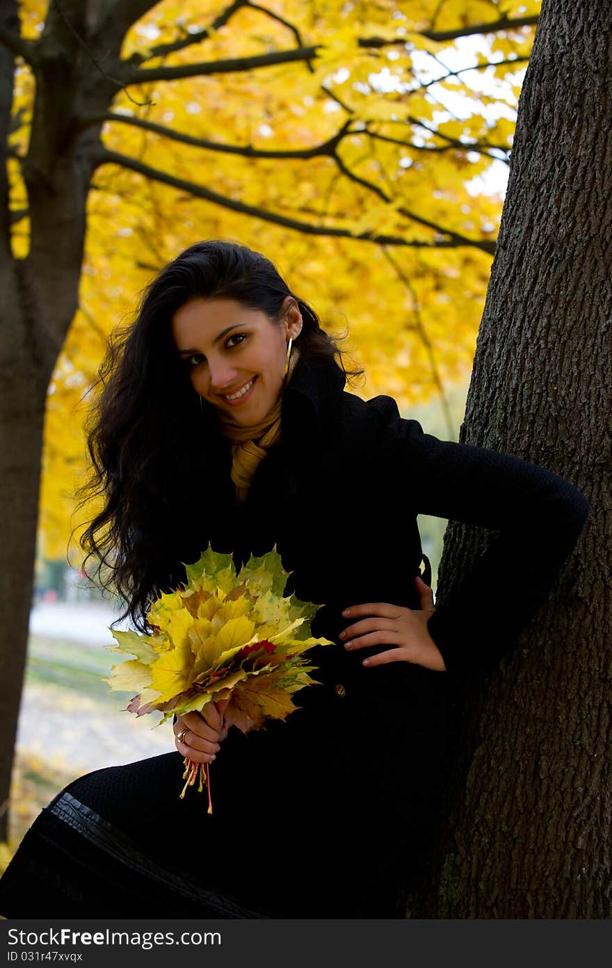 The young girl smiles sitting on leaves. The young girl smiles sitting on leaves