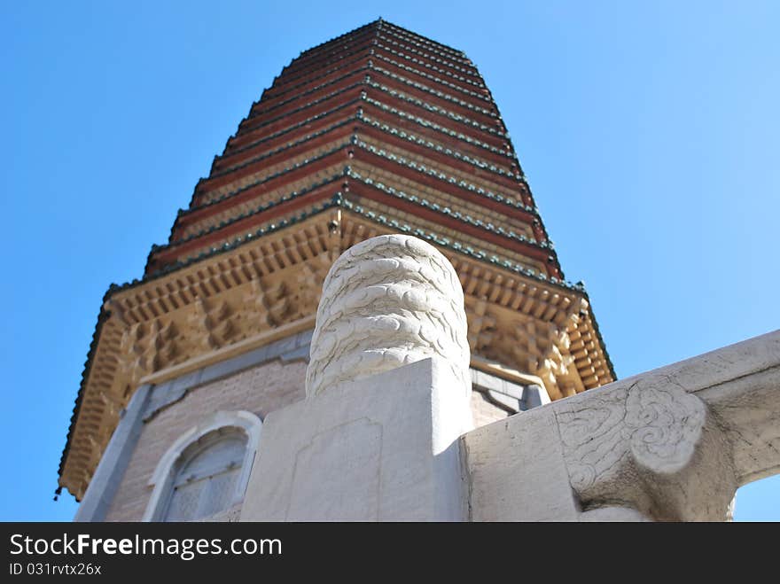 Close-up of a white stone handrail detail with an out of focus buddhist pagoda tower over a blue sky at Beijing, China. Shallow depth-of-field. Close-up of a white stone handrail detail with an out of focus buddhist pagoda tower over a blue sky at Beijing, China. Shallow depth-of-field