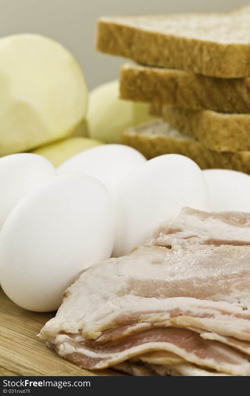 Raw ingredient ready to cook a gourmet meal breakfast. Food on a wooden cutting board. Potato,egg,bacon and whole wheat bread. Orientation : vertical Concept : cooking, mealtime,morning,. Raw ingredient ready to cook a gourmet meal breakfast. Food on a wooden cutting board. Potato,egg,bacon and whole wheat bread. Orientation : vertical Concept : cooking, mealtime,morning,