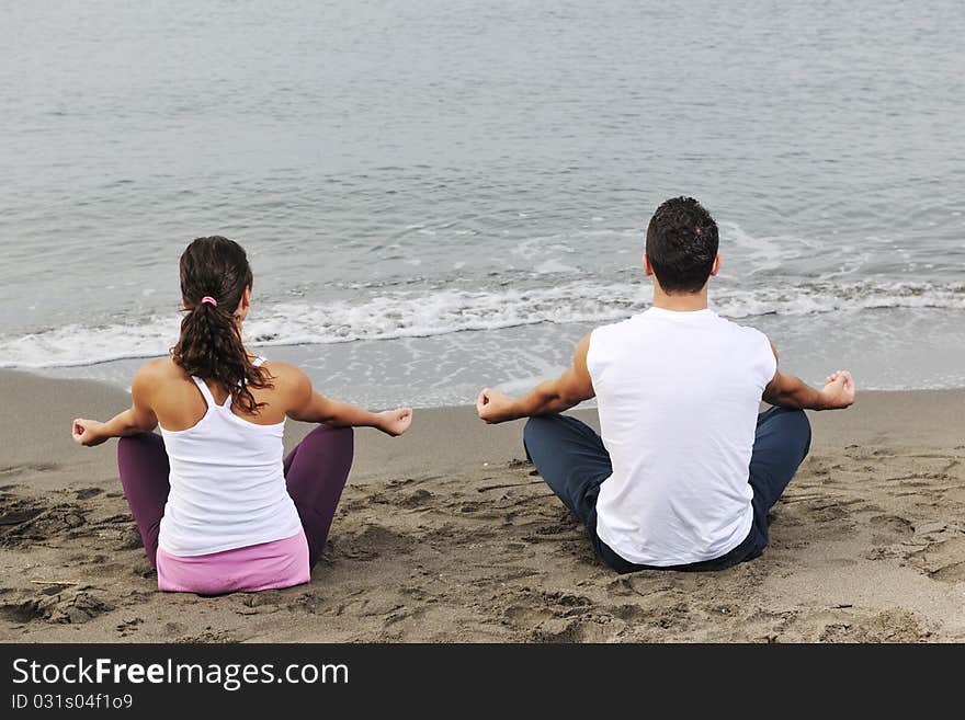 Young couple people meditating yoga in lotus position at early morning on the beach. Young couple people meditating yoga in lotus position at early morning on the beach