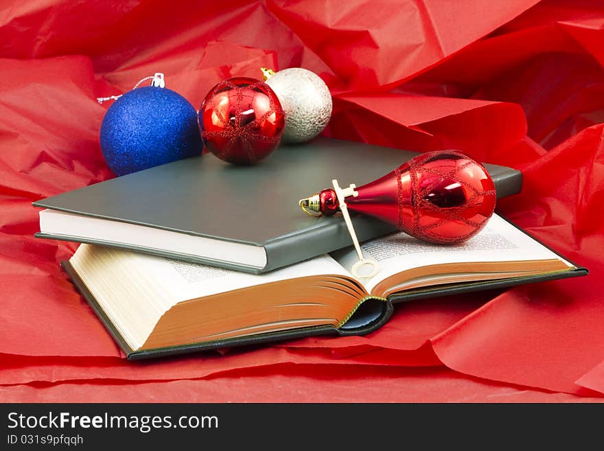 Golden key and open book and closed book on red paper with holiday ornaments reflect the gift that opens knowledge. Golden key and open book and closed book on red paper with holiday ornaments reflect the gift that opens knowledge