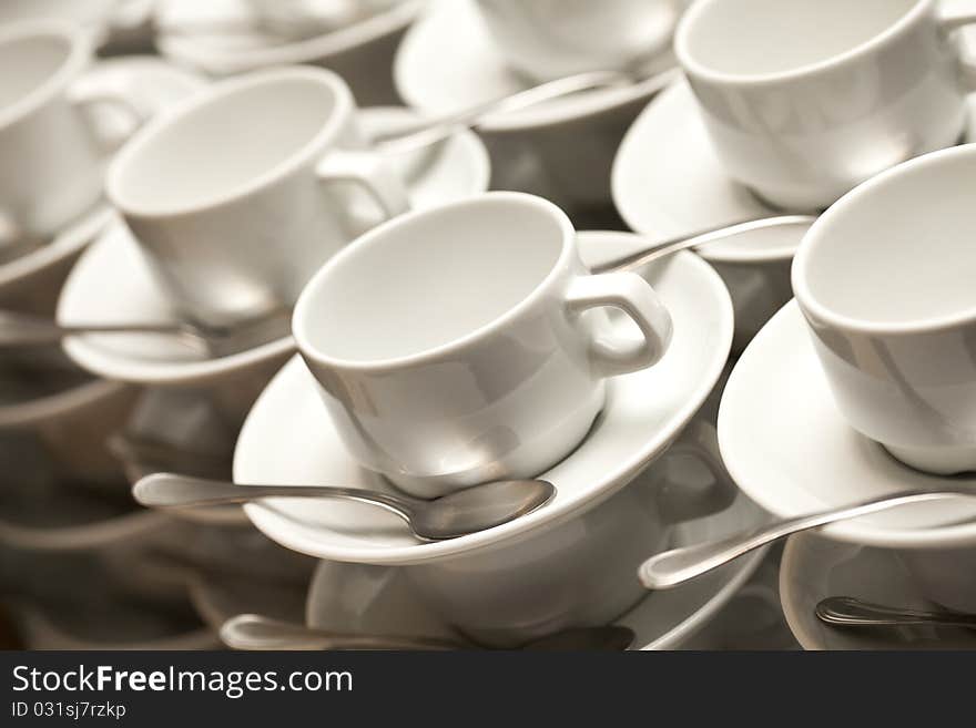 Stacked empty teacups with teaspoons at a function over white background