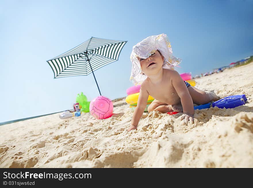 Little baby girl on the sand beach with hat and beach toys. Little baby girl on the sand beach with hat and beach toys