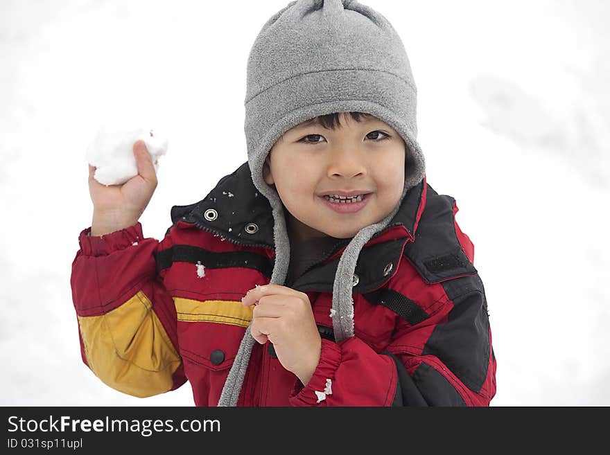 A young boy holds a snowball and looks like he is ready to throw it. A young boy holds a snowball and looks like he is ready to throw it.