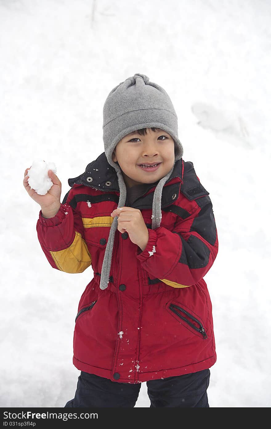 A young boy holds a snowball and looks like he is ready to throw it. A young boy holds a snowball and looks like he is ready to throw it.