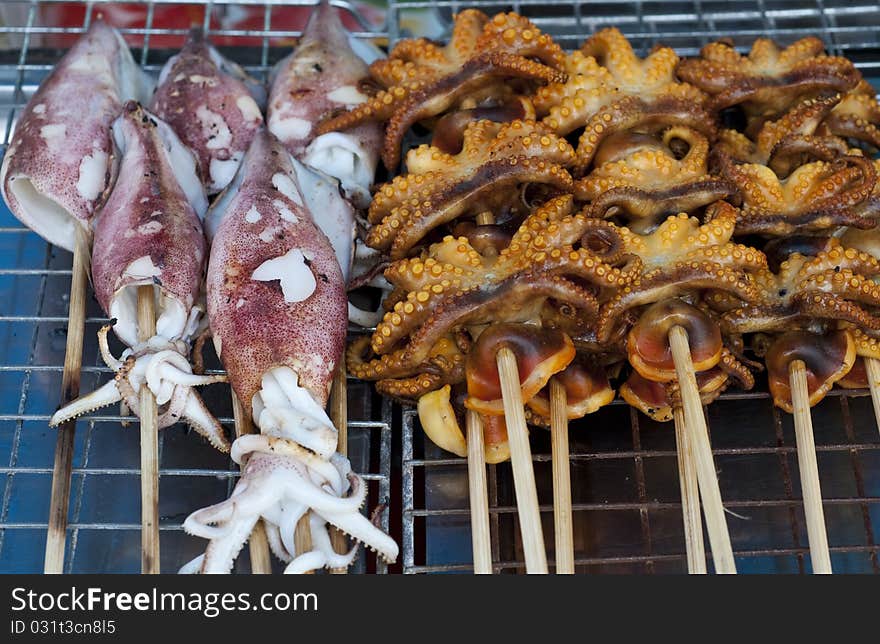 Grilled Squids and octopus heads sold in a Thai market