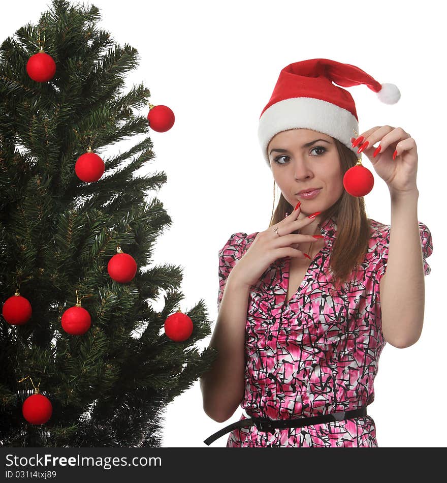 Woman in a Christmas hat decorate a Christmas tree. Woman in a Christmas hat decorate a Christmas tree