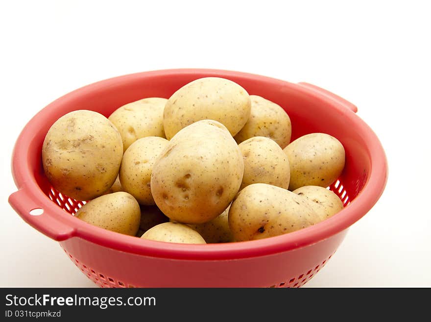 Potatoes in the red kitchen sieve. Potatoes in the red kitchen sieve