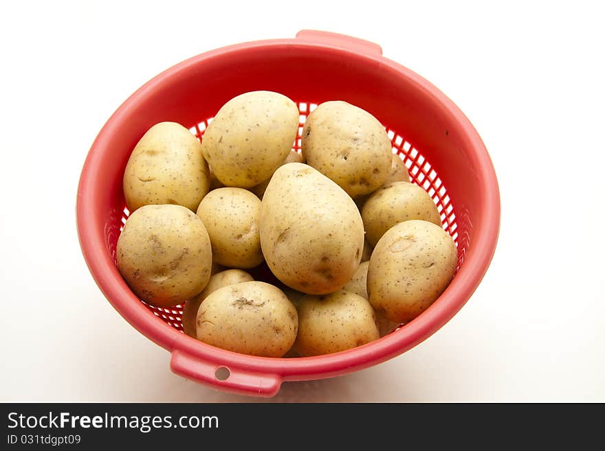 Potatoes in the red kitchen sieve. Potatoes in the red kitchen sieve