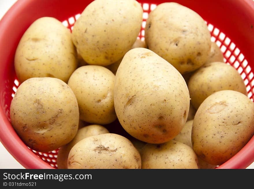 Potatoes in the red kitchen sieve. Potatoes in the red kitchen sieve